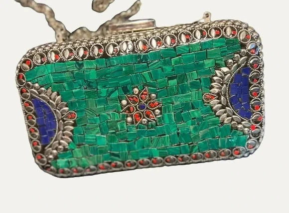Green mosaic clutch with silver accents on a denim background